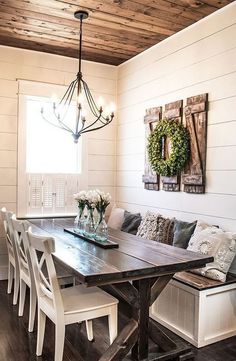 a dining room table with white chairs and benches in front of it, surrounded by wood plank ceilinging