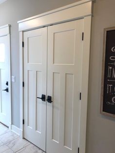 three white doors in a room with tile flooring and wall hanging on the wall