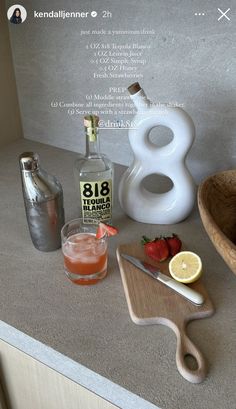 a counter top with some drinks on it and a cutting board next to the bottle