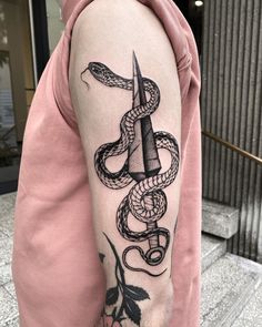 a man with a tattoo on his arm holding a knife and snake wrapped around it