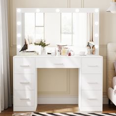 a white vanity with lights on it in front of a window and a chair next to it