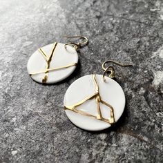 "White elegant Kintsugi inspired earrings. Crafted from fine bone china porcelain, each pair showcase unique pattern plated with genuine gold. They come in two sizes  50mm/2\" diameter and 35mm/1.37\". They hang on stainless steel or brass hooks plated with real gold. The back of earrings has a white matte finish. Arriving in a lovely gift box, these earrings are a true treasure. Embrace the art of restoration and elevate your style with our Kintsugi-inspired porcelain earrings. This makes a meaningful gift to a person who overcomes any life difficulties and is a symbol of strenght and resilience . This earrings have never been broken, they are only inspired by Kinstugi. The video shows the smaller pair." White Brass Earrings As Gift, Nickel Free White Circle Earrings, White Round Pendant Earrings For Gifts, White Round Pendant Earrings As A Gift, Modern White Brass Jewelry, White Brass Earrings For Gift, White Ceramic Jewelry As A Gift, White Ceramic Jewelry For Gifts, White Ceramic Jewelry Gift