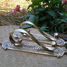 a pair of metal handles sitting on top of a wooden table next to some flowers