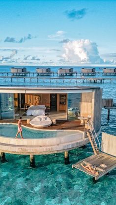 a woman is walking into the water from a floating house in the middle of the ocean