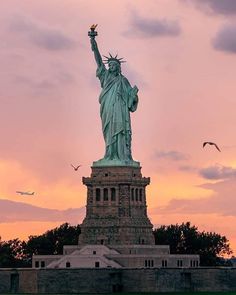 the statue of liberty is lit up at sunset