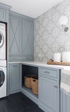 a washer and dryer in a laundry room next to cabinets with baskets on them