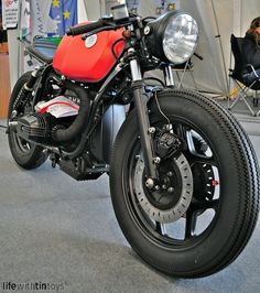 a red and black motorcycle on display in a showroom with people sitting at tables