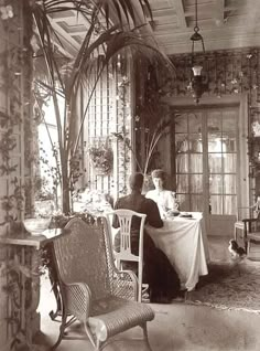 an old black and white photo of two people sitting at a table in a room