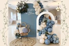 a baby shower is decorated with blue and white balloons, greenery, and an arch