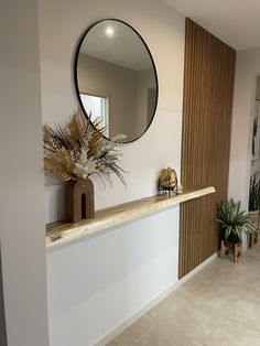 there is a mirror and some plants on the counter in this room with tile flooring