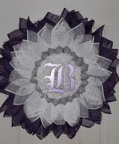 a purple and white wreath with the letter b on it's center piece is hanging on a door