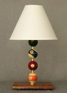 a lamp that is sitting on top of a wooden base with pool balls in it