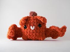 an orange crocheted stuffed animal with a tiny hat on its head and eyes