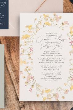 the wedding stationery is laid out on a wooden table