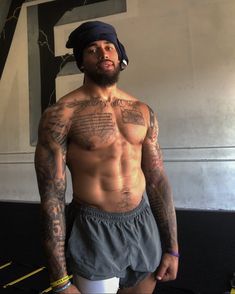 a shirtless man with tattoos standing in a gym