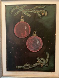 two christmas ornaments hanging from a tree branch in front of a chalkboard with writing on it