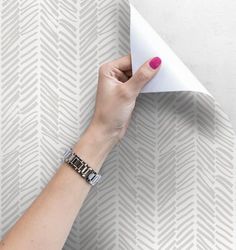 a woman's hand holding an origami piece of paper over a wall