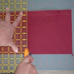 a person cutting fabric with a pair of scissors on top of the table next to it