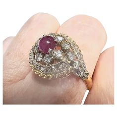 This Art Deco-style ring from the 1920-1925 period is crafted in 18K gold with platinum accents and features Diamonds and a ruby cabochon. It has a weight of 4.12 grams and is sized 15.5/55.5. The Diamonds are simple-cut, totaling 0.90 carats, and are of SI-VS clarity and H-G color grade. The other gemstone is a ruby cabochon weighing 0.80 carats. The ring measures 2.2 cm in length and 1.5 cm in width. The gemstones are set in claw settings. **IN STOCK** Characteristics: Material: 18K Gold with Hallmarked Oval Ruby Ring In Art Deco Style, Art Deco Hallmarked Oval Ruby Ring, Art Deco Oval Ruby Ring, Antique Diamond Cabochon Rings, Vintage Diamond Cabochon Rings, Vintage Diamond Rings With Cabochon, Art Deco 14k Stamped Round Ruby Ring, Art Deco 14k Stamped Ruby Ring, Antique Ruby Cabochon Ring