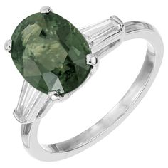 Art Deco 1930's, Sapphire and Diamond engagement ring. GIA certified oval, natural green sapphire set in a platinum three-stone setting with 2 tapered baguette side diamonds. This green sapphire is certified, no heat and no enhancements. The beautiful color of this stone can not quite be captured in photos. 1 oval natural sapphire. 3.80ct. Bluish green. VS2 to SI1. GIA certificate# 2145836040. 4.80x10.44x7.98mm 2 tapered baguette diamonds. .20ct. G to H color, VS2 clarity. Size 7 and sizable Tested: Platinum 4.3 grams 10.04mm wide at top 8.9mm high at top 1.5mm wide at bottom Classic Oval Green Sapphire Ring, Classic Green Sapphire Oval Ring, Gia Certified Green Oval Sapphire Ring, Classic Green Oval Sapphire Ring, Green Oval Sapphire Ring For Formal Occasions, Classic Oval Three-stone Emerald Ring, Classic Oval Emerald Ring With Three Stones, Classic Green Sapphire Ring With Brilliant Cut, Classic Green Sapphire Ring With Center Stone