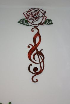 a metal rose with musical notes hanging on the wall next to a vase filled with flowers