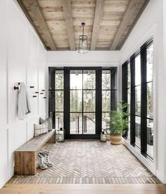 the entryway is decorated in white and black with herringbone tile flooring that matches the wood ceiling