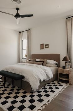 a bedroom with a large bed and black and white checkered rug on the floor