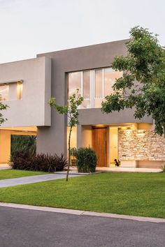 a modern house with grass and trees in the front yard