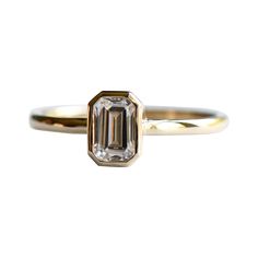 an emerald cut diamond ring on a white background