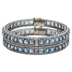 Pair of London blue topaz and diamond bangles mounted in sterling silver with a 14k gold tongue clasp and safety. Each bracelet contains princess cut blue topaz prong set down the center with round diamonds along the side edges.  The 2 bracelets have a combined carat weight of 5.28 carats in diamonds and 61.23 in London blue topaz.  Internal circumference is 7.12".  across inside 2 3/8" by 2 5/16" Elegant Blue Topaz Jewelry With Single Cut Diamonds, Formal Stackable Blue Topaz Jewelry, Luxury Blue Topaz Bracelets For Formal Occasions, Blue Topaz Gemstone Bangle Jewelry, Blue Topaz Bangle Jewelry Gift, Blue Topaz Bangle Jewelry, Fine Jewelry Blue Topaz Bracelets, Luxury Jewelry With Rose Cut Diamonds And Blue Topaz, Luxury Blue Topaz Jewelry With Rose Cut Diamonds