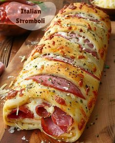 an italian stromboli with meat and cheese on a cutting board next to other food