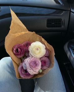 a person holding a bouquet of flowers in their lap while sitting in the back seat of a car