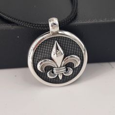 A high-quality Sterling silver pendant. ⚜   Fleur de Lis mans silver pendant. 🔳 Round gothic style, man-size but not only,  ⚔   knights pendant, strong and beautiful form a 925 sterling-silver item you will adore.  📜 Handmad engraved Fleur De Lis symbols on top and on the two bands, special        handcraft black patent finishing. Hard hand-polished piece!  ⚖ Weight.9.0grs ✍ Designed and created by Babuco Jewellery Athens. ♻ A recycled item. 💍 Best gift for you!  🎁 Box included!v 😊 Thanks for stopping by! ✈ Do You need faster shipping? Purchase EXPRESS SHIPPING also from my listings! 🛠   Free services to renew your beloved jewels purchased from my shop.          You will charge only for the shipping costs. Medieval Sterling Silver Necklace In Silver, Medieval Sterling Silver Jewelry In Antique Silver, Handmade Medieval Silver Necklaces, Silver Gothic Locket Jewelry, Medieval Sterling Silver Pendant Jewelry, Medieval Style Silver Jewelry Gift, Medieval Style Silver Engraved Necklace, Gothic Sterling Silver Necklaces In Silver, Gothic Sterling Silver Necklaces