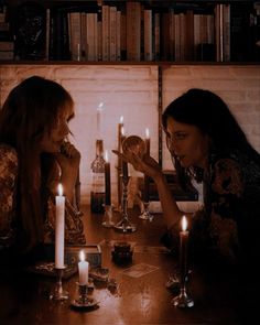 two women sitting at a table with candles in front of them