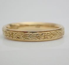 a gold wedding band that has been engraved with flowers and leaves on the inside of it