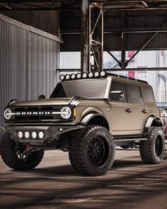 an off - road vehicle is parked in a warehouse with large tires and lights on