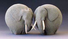 two gray elephants facing each other with their trunks touching trunk heads to the opposite direction