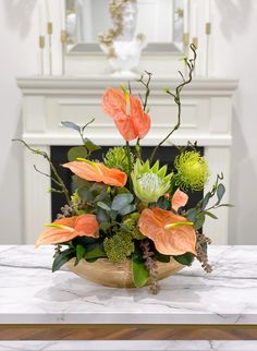 an arrangement of flowers on a table in front of a fireplace