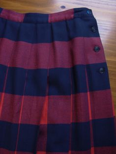 One vintage 1980's red and navy plaid pleated wool skirt, women's size 10 * Sits at the natural waist. * 4 button closures on the side of the skirt. * Fully pleated all the way around. * Wool fabric. * Midi length (mid calf). * Color scheme: red and navy blue. | CONDITION | A-. One small hole in the fabric. Gently used vintage item. | BRAND | David Brooks Ltd. Made in USA. | SIZE | Marked as a women's 10 (USA). PLEASE compare the measurements below to a similar item that fits you for the best si Preppy Pleated Skirt Bottoms For Fall, Plaid Pleated Skirt For School In Fall, Plaid Bottoms For School In Fall, Fall School Uniform Pleated Skirt, Accordion Pleated Full Skirt For Fall, Full Skirt With Accordion Pleats For Fall, Fall Pleated School Uniform Bottoms, Fall School Uniform Style Pleated Bottoms, Pleated School Uniform Bottoms For Fall