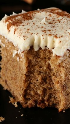 a piece of cake with white frosting and sprinkles on it sitting on a black surface