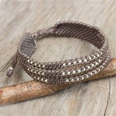 two brown and white beaded bracelets sitting on top of a wooden stick