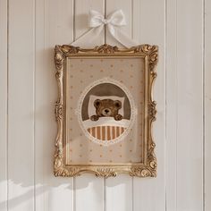 a teddy bear is hanging on the wall with a bow around it's neck