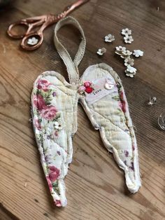 an angel ornament sitting on top of a wooden table next to scissors and beads