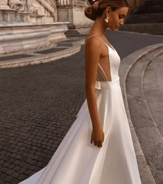 a woman in a white dress is walking down the street