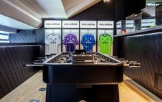 the inside of a store with many different colored shirts on display in front of them