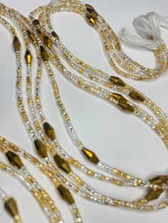 Why You'll Love It: Elegant Design: The delicate blend of gold and clear glass seed beads, highlighted by larger gold crystal glass accents, creates a timeless and refined look. High-Quality Materials: Crafted with premium glass seed beads and crystal glass accents, ensuring durability and a lasting shine. Adjustable Fit: Designed for comfort and versatility, this waist bead adjusts to fit perfectly. Versatile Style: Perfect for everyday wear, special occasions, or as a meaningful gift. Cultural Elegant Yellow Beaded Bracelets With Gold Beads, Elegant Yellow Beaded Bracelet With Gold Beads, Gold Rhinestone Necklaces For Celebration, Adjustable Gold Beaded Bracelet With Faceted Beads, Elegant Adjustable Beaded Crystals, Gold Crystal Jewelry With Gold Beads, Adjustable Gold Beaded Bracelets In Czech Glass, Adjustable Gold Beaded Bracelets Made Of Czech Glass, Gold Multi-strand Beaded Bracelet