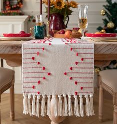 the table is set for christmas dinner with red and white decorations on it, along with wine glasses