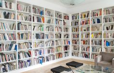 a room filled with lots of white bookshelves next to a glass coffee table