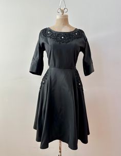 "A darling little black dress from the late '40s/early '50s.  Swishy black taffeta with gorgeous raised taffeta appliqué swirls and prong set rhinestone detail with the occasional faux pearl bead.  This babe has pockets on each hip seam, the original side metal zipper and is unlined, lightweight, clean and ready to wear.  The label has worn a bit but looks like it was a Du-Rite.  There are repairs at each underarm that are sturdy and only visible if your arms are raised (even then it's black and not very noticeable ). Otherwise in perfect condition with no other flaws to note. Please see photos for details.  ~ Measurements ~  Size: S Bust: 34\"- 36\" max Waist: 26\" (27\" very snug) Hip: open Bodice Length: 15.5\" Skirt Length: 25\"" Metal Zipper, Dress Clothes For Women, Skirt Length, The Label, Faux Pearl, Bodice, Ready To Wear, Little Black Dress, Cocktail Dress