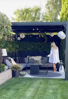 a woman standing in the middle of a backyard with furniture and decorations on it's lawn